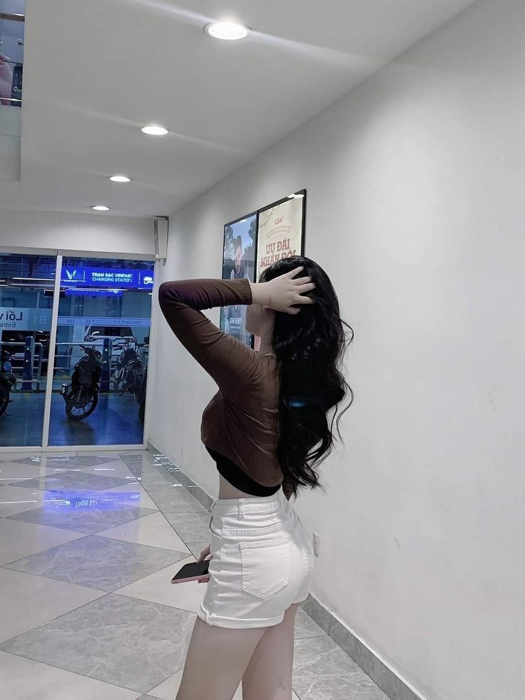 Cô gái trẻ mặc áo dài tay màu nâu và quần shorts trắng đẹp