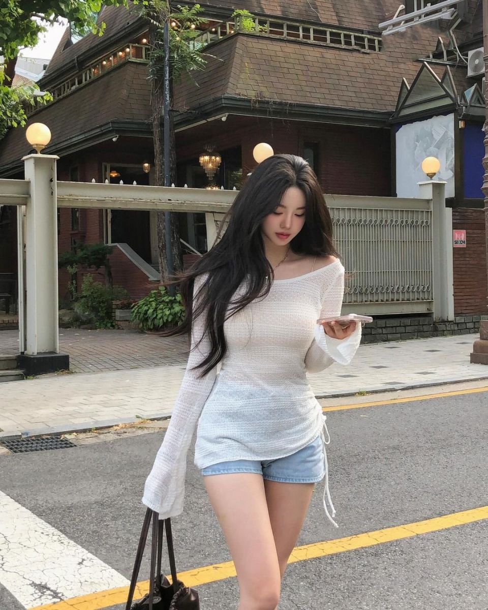 Cô gái trẻ mặc áo dài trắng và quần short denim đậm chất phố