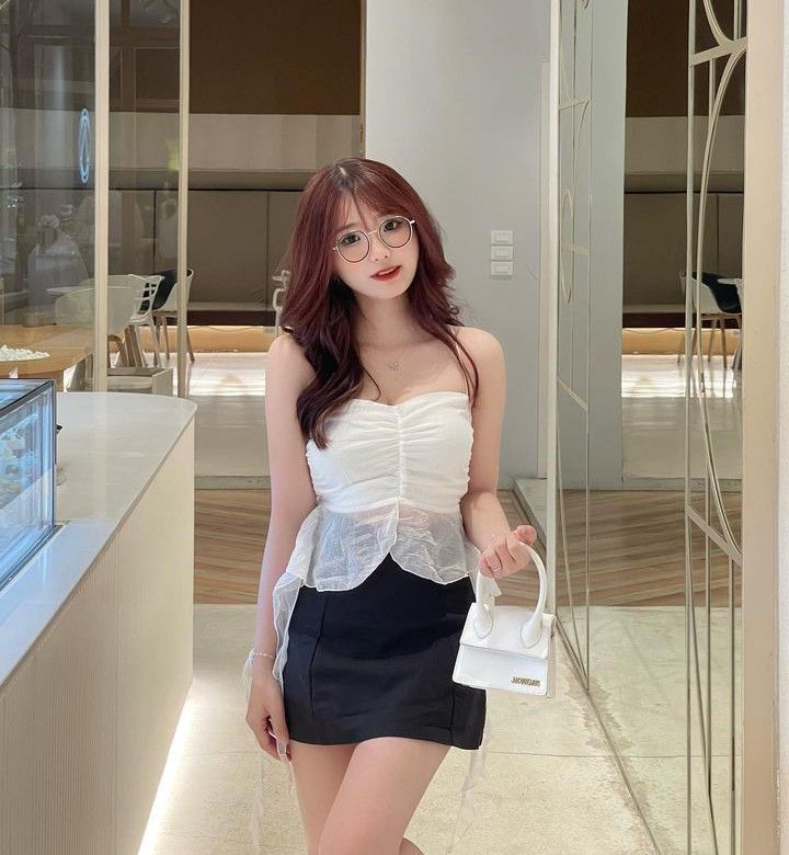 Cô gái trẻ mặc áo hai dây trắng và chân váy đen