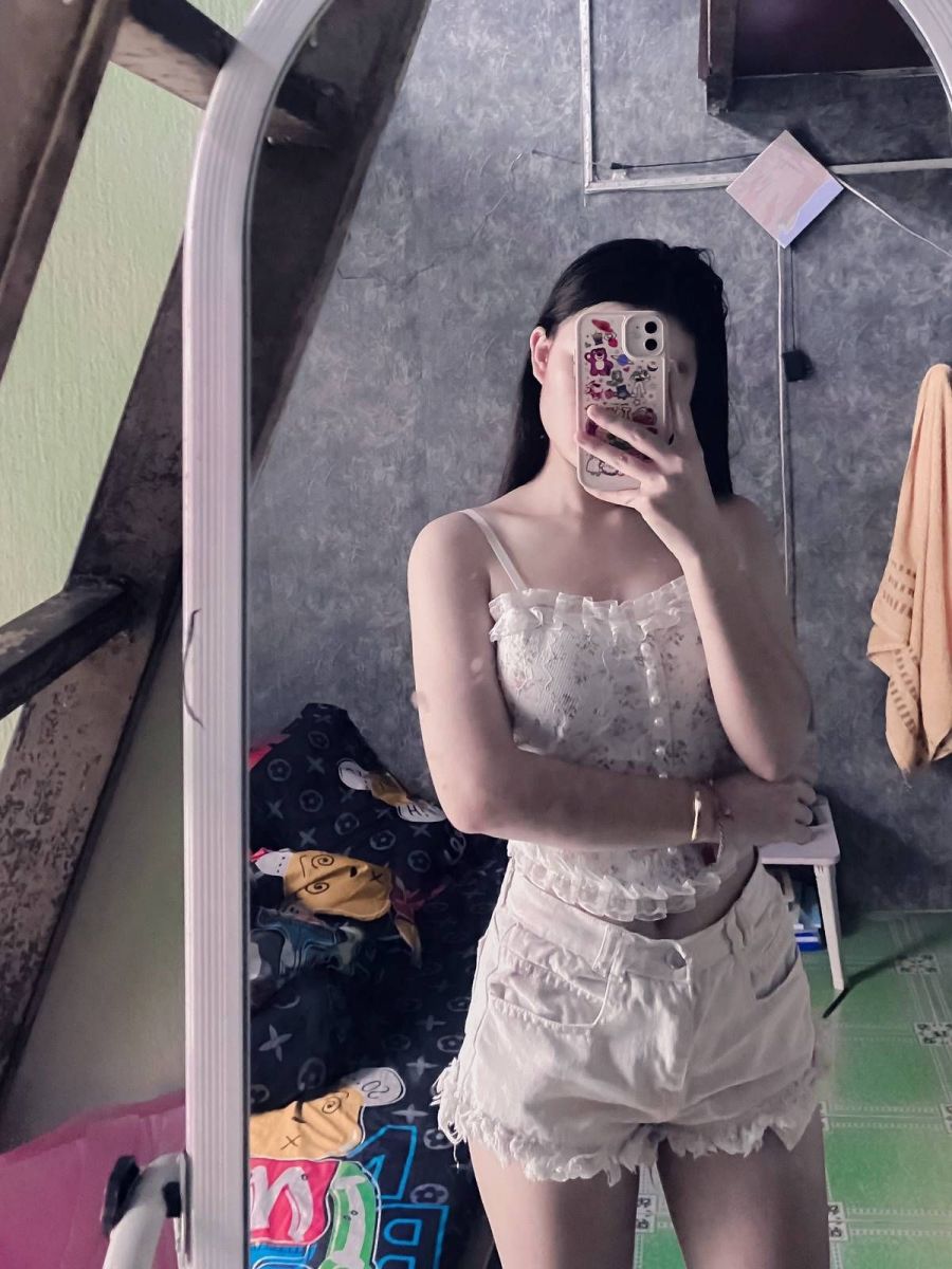 Cô gái trẻ mặc áo hai dây trắng và quần shorts sáng màu
