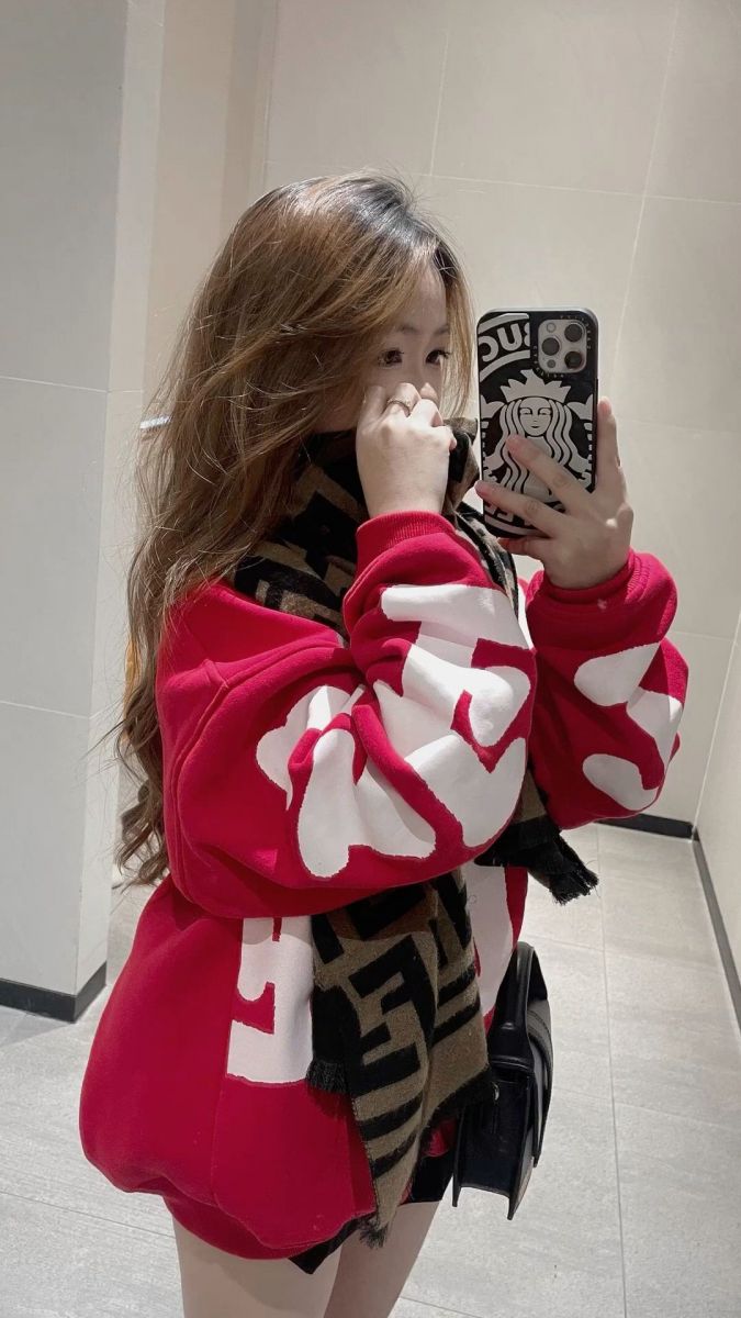 Cô gái trẻ mặc áo hoodie đỏ và khăn quàng trong không gian nhà tắm