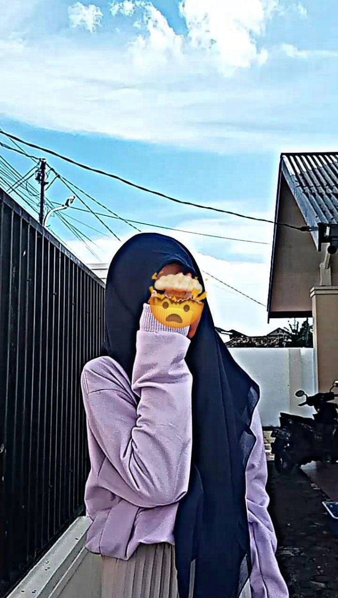 Cô gái trẻ mặc áo khoác dài hồng và khăn hijab đen che mặt