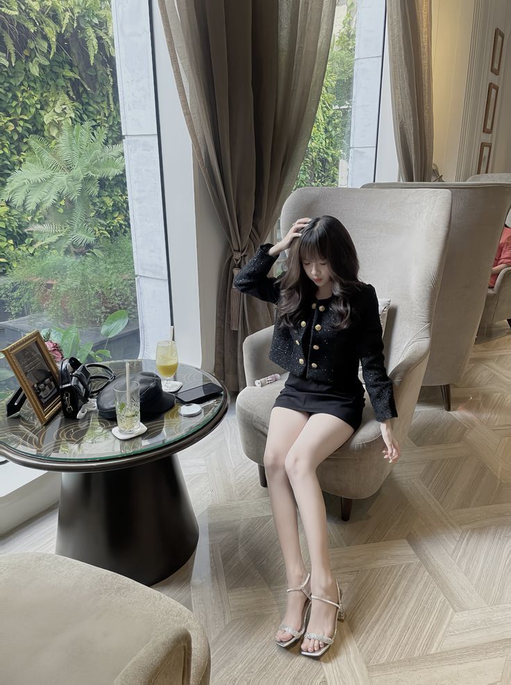 Cô gái trẻ mặc áo khoác đen và chân váy ngắn trên ghế sofa