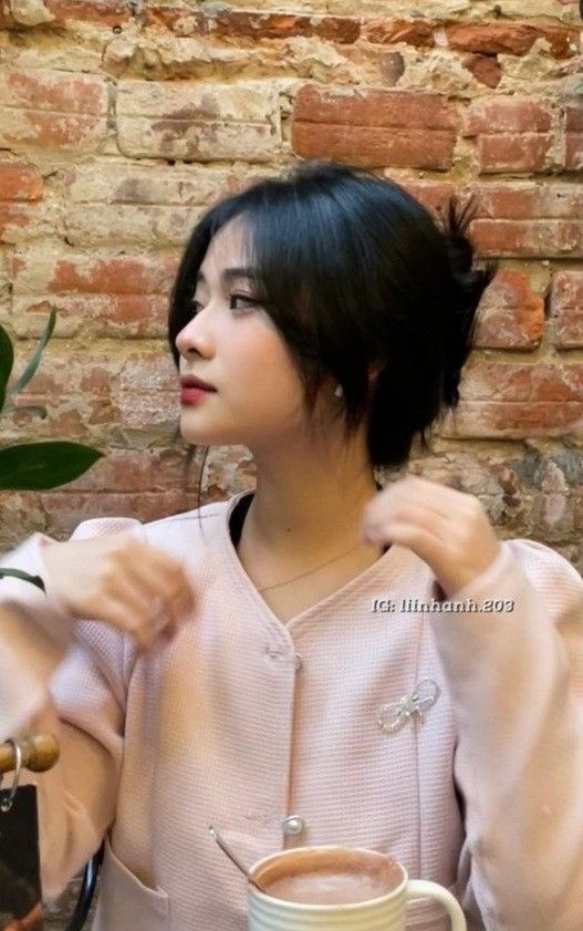 Cô gái trẻ mặc áo khoác hồng ngồi trong quán cafe