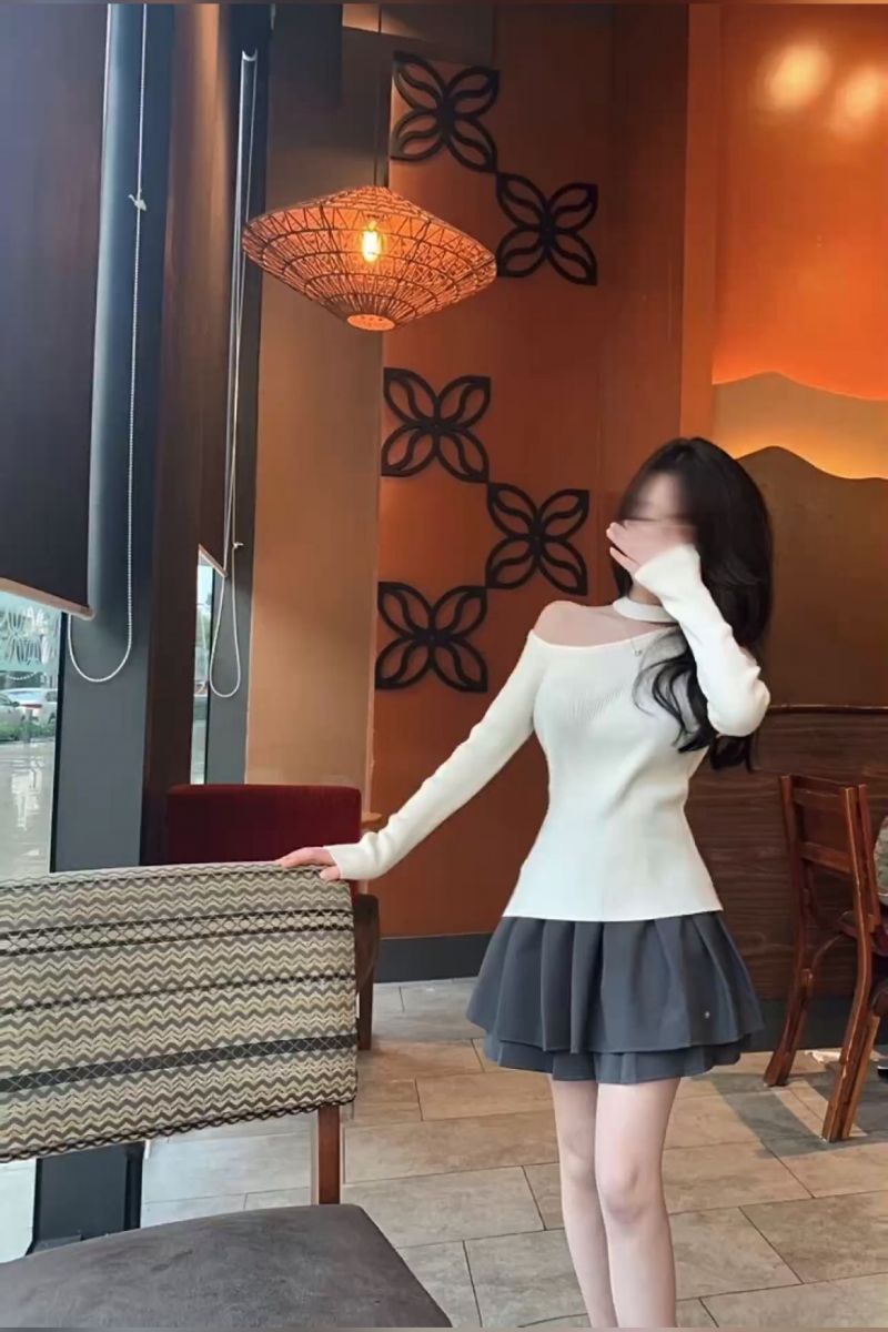 Cô gái trẻ mặc áo len trắng và chân váy xám