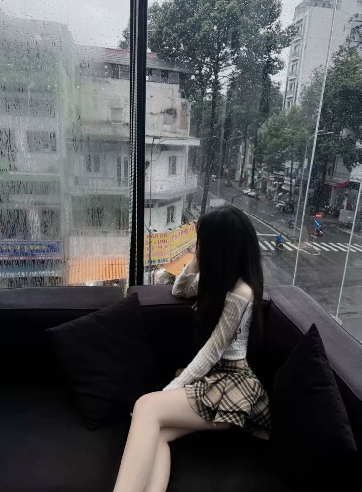 Cô gái trẻ mặc áo len trắng và chân váy xinh đẹp bên cửa sổ
