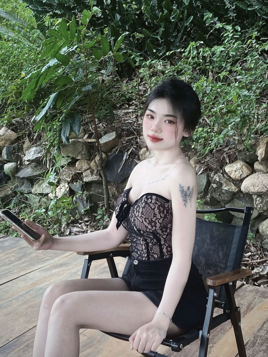 Cô gái trẻ mặc áo lót ren và quần shorts đen trên ghế gỗ