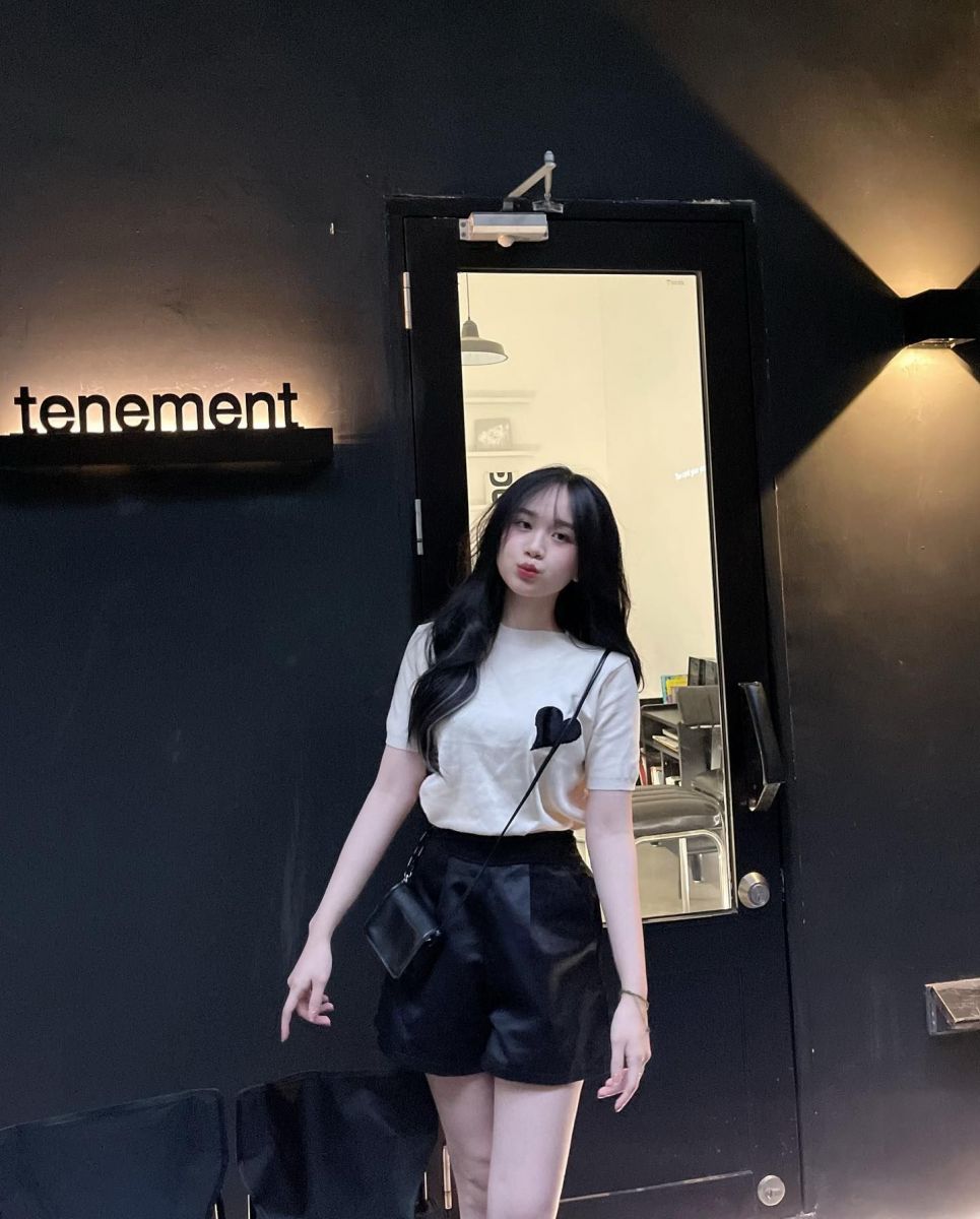 Cô gái trẻ mặc áo phông trắng họa tiết và quần short đen