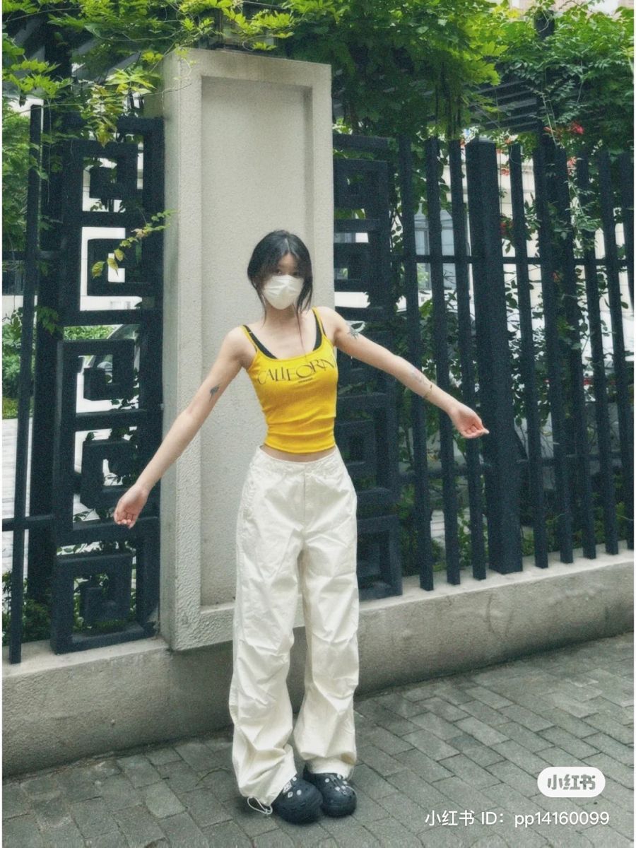 Cô gái trẻ mặc áo tank top vàng và quần trắng tạo dáng tươi tắn