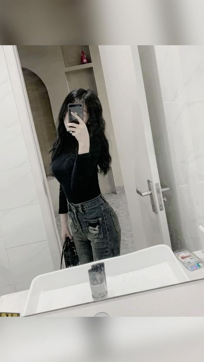 Cô gái trẻ mặc áo thun đen và quần jeans rách tạo dáng selfie