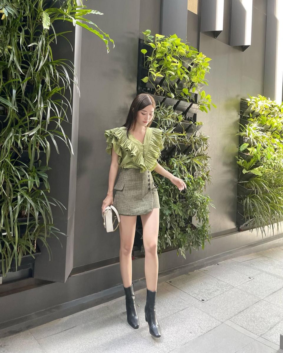 Cô gái trẻ mặc blouse xanh lá kết hợp chân váy và boots cao cổ