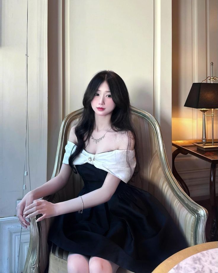 Cô gái trẻ mặc đầm đen ngồi trên ghế salon vàng