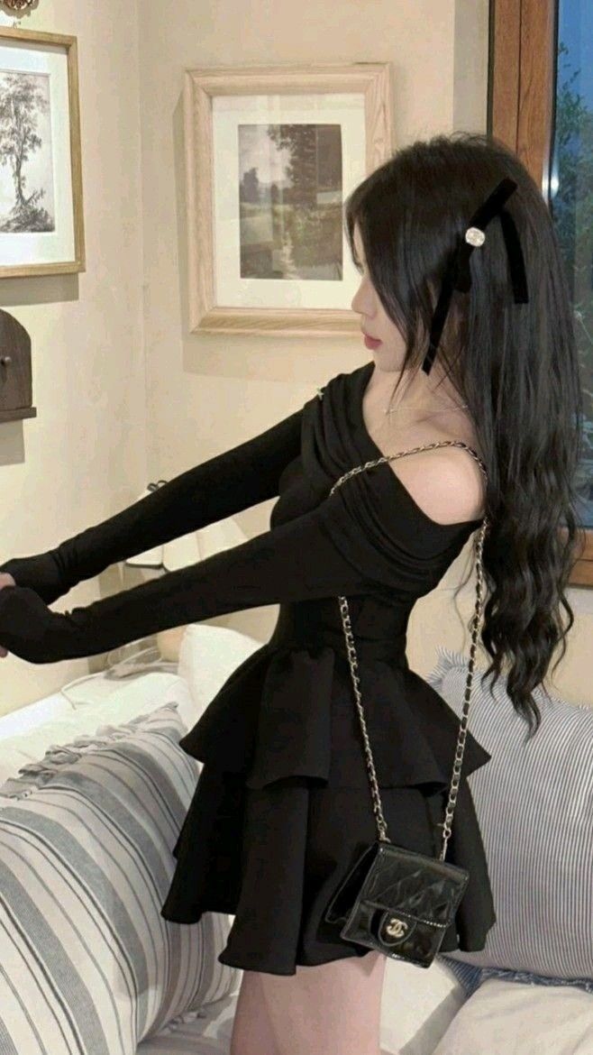 Cô gái trẻ mặc đầm đen tây dài với túi xách nhỏ