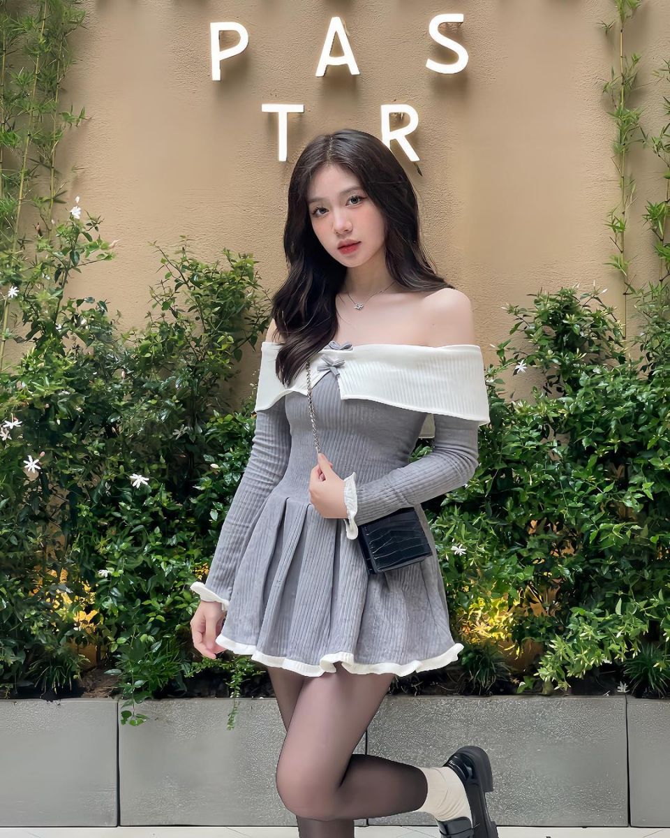 Cô gái trẻ mặc đầm ngắn màu xám bên cây cỏ xanh mát