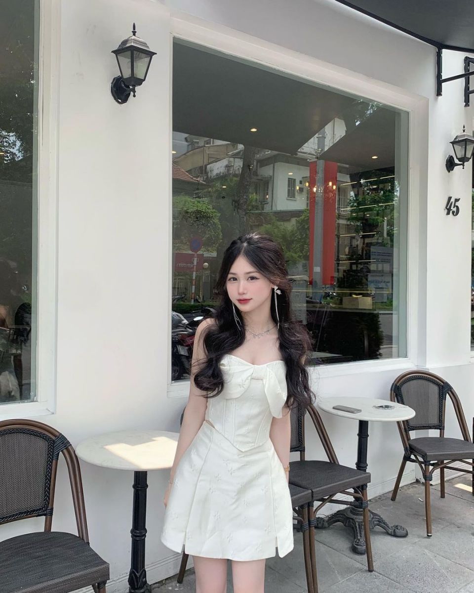 Cô gái trẻ mặc đầm trắng tại quán cà phê đẹp