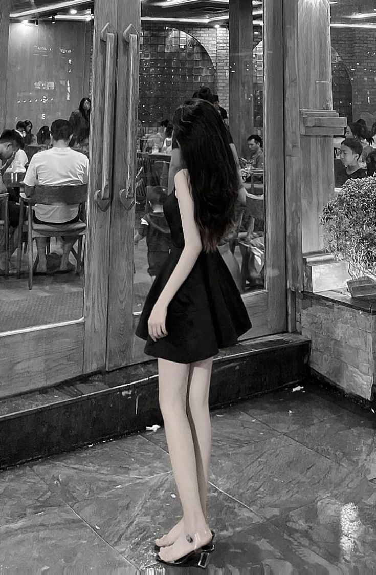 Cô gái trẻ mặc váy đen giữa quán ăn đông người