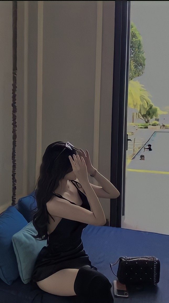 Cô gái trẻ mặc váy đen ngồi trên ghế sofa che mặt