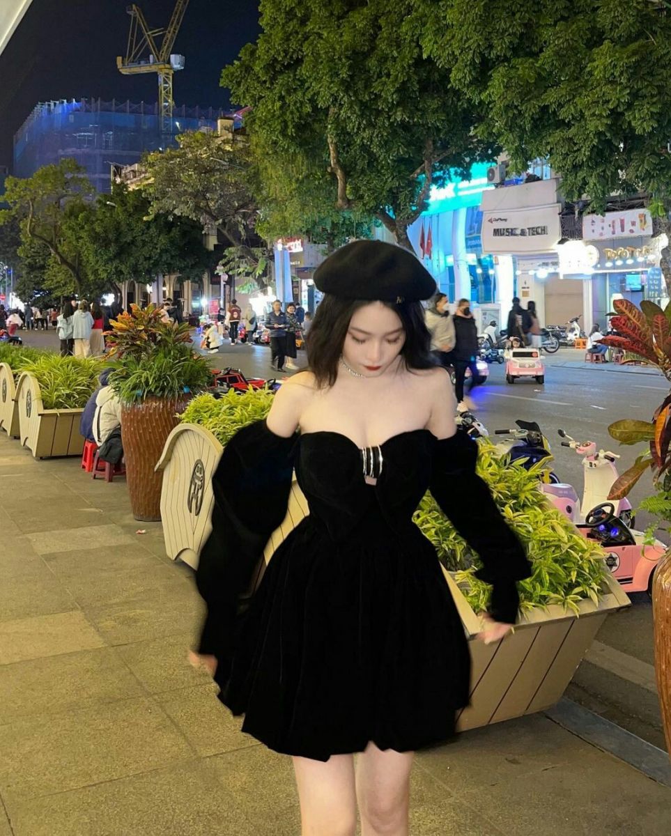 Cô gái trẻ mặc váy đen và mũ beret trên phố