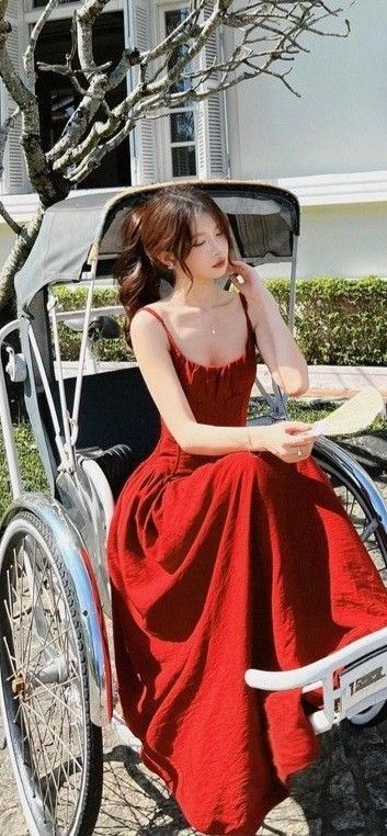 Cô gái trẻ mặc váy đỏ ngồi trên xe đạp cổ điển