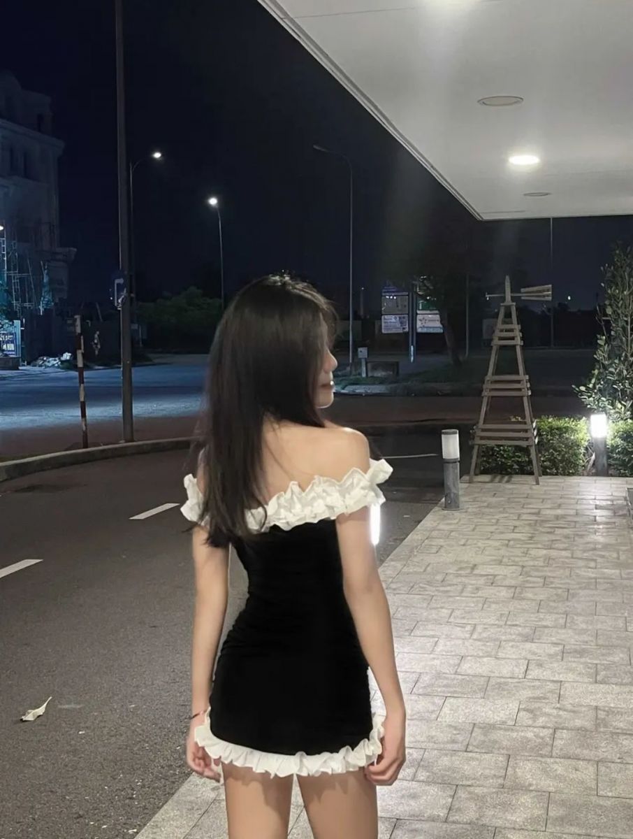 Cô gái trẻ mặc váy ngắn màu đen viền trắng giữa phố
