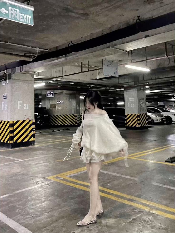 Cô gái trẻ mặc váy trắng, đi bộ chậm chậm trong bãi đỗ xe