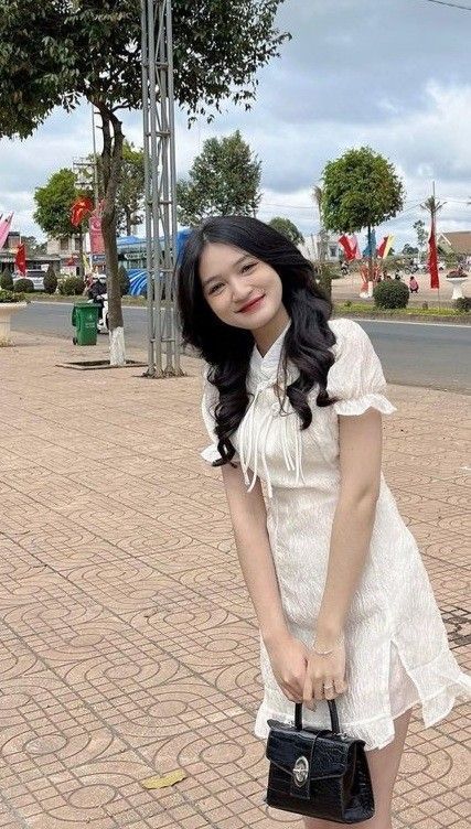 Cô gái trẻ mặc váy trắng dịu dàng trên phố