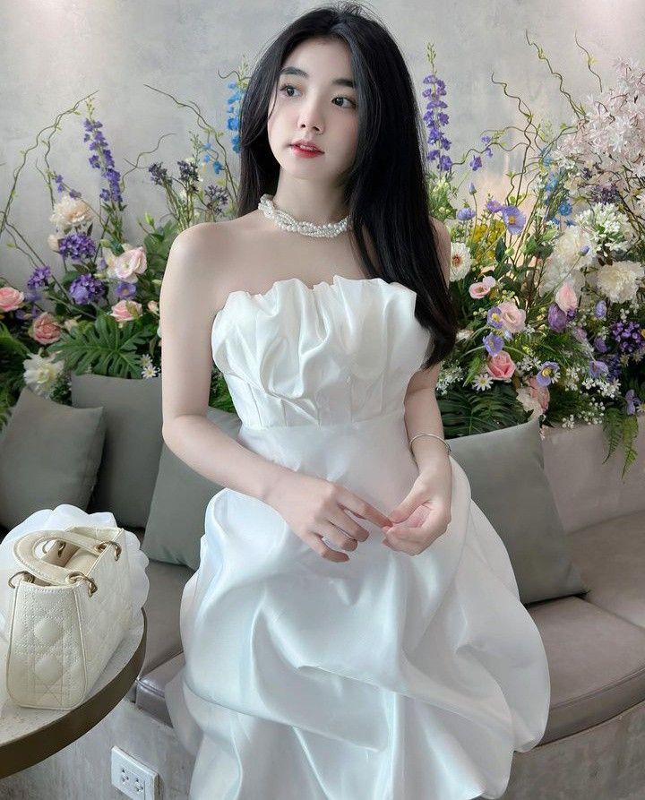 Cô gái trẻ mặc váy trắng giữa không gian trang trí hoa tươi