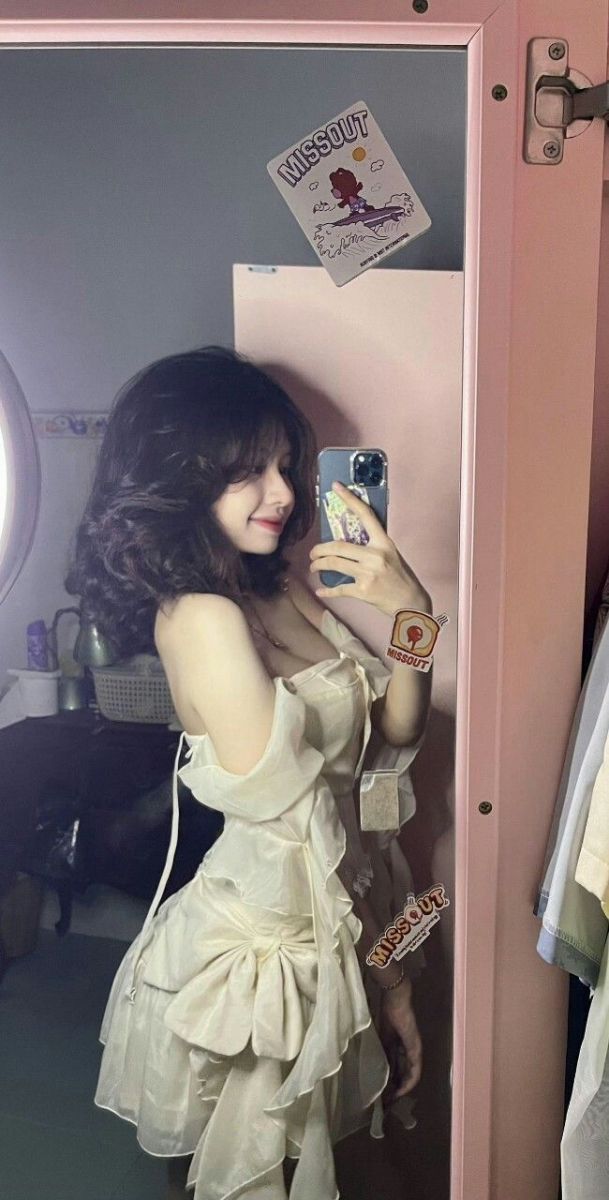 Cô gái trẻ mặc váy trắng nhiều tầng chụp ảnh selfie với gương lớn