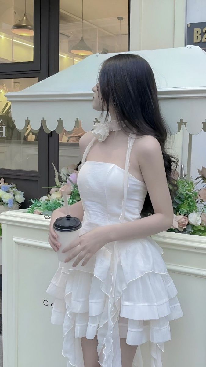 Cô gái trẻ mặc váy trắng xòe dịu dàng tại quán cà phê