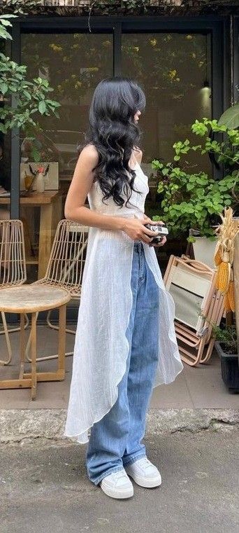 Cô gái trẻ trong áo dài trắng và quần jeans rông