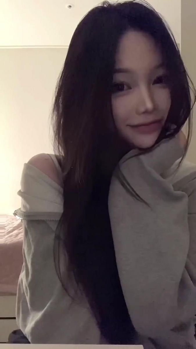 Cô gái trẻ trong áo hoodie xám trên giường