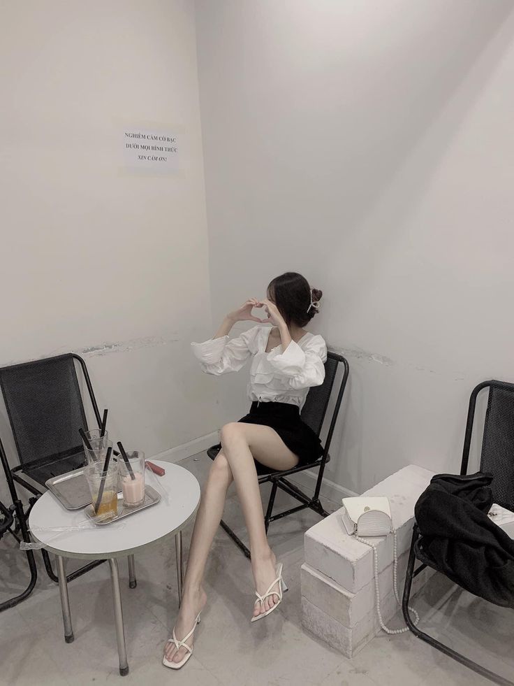 Cô gái trẻ trong bộ áo blouse trắng và chân váy đen tại quán cà phê