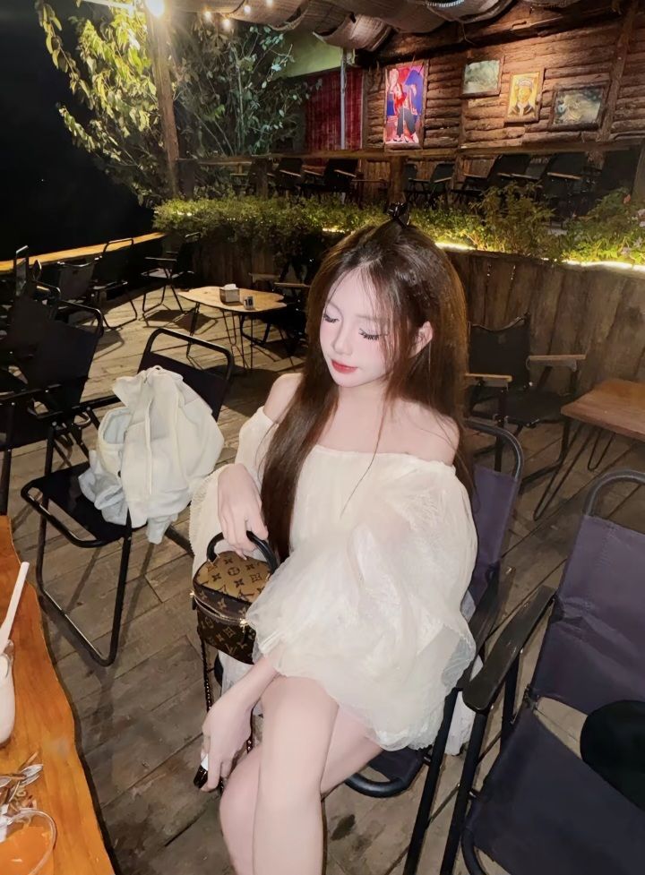 Cô gái trẻ tự tin trong áo bông trắng tại quán cà phê ngoài trời