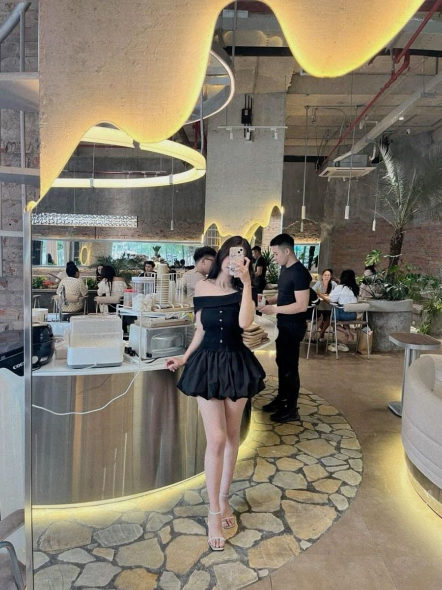 Cô gái trẻ với áo crop top đen và chân váy xòe chụp ảnh trước gương