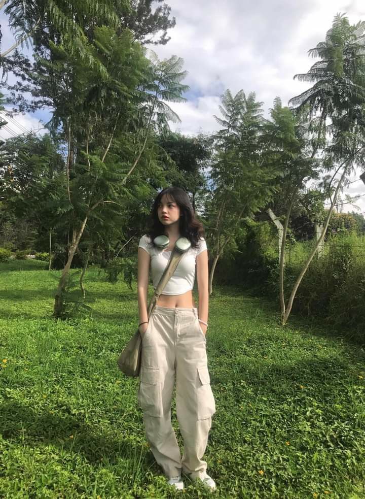 Cô gái trẻ với áo crop top trắng giữa rừng xanh