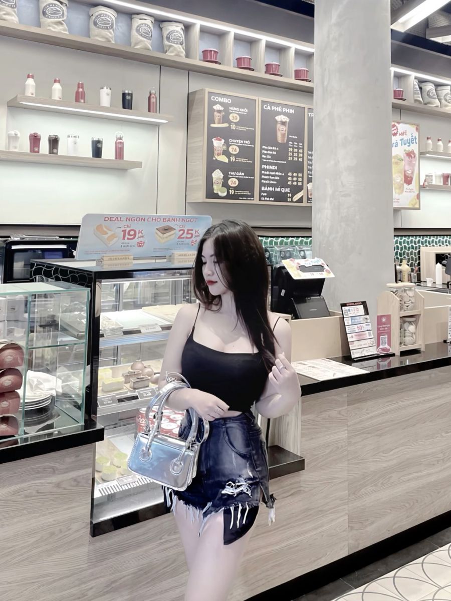 Cô gái trẻ xinh đẹp mặc áo tank top đen và chân váy denim