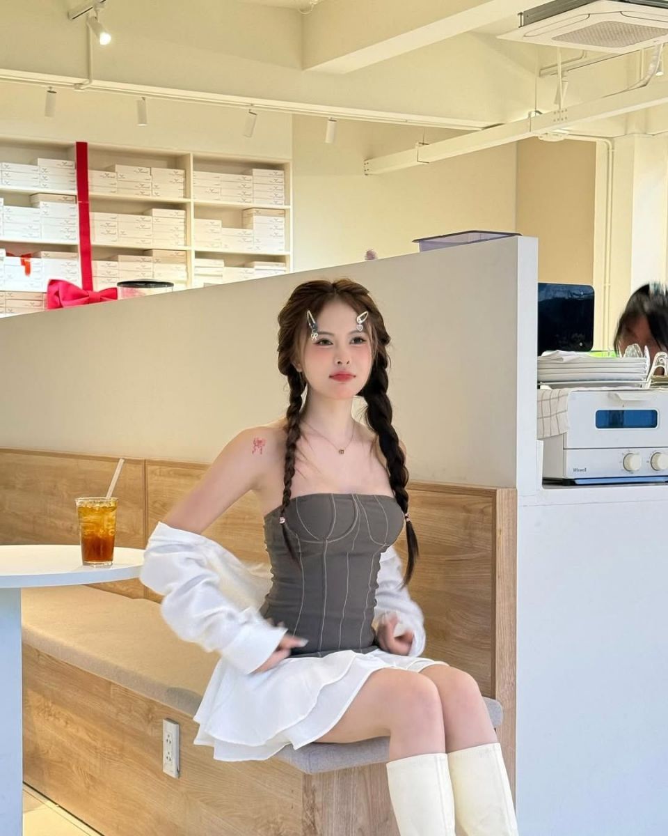 Cô gái trẻ xinh đẹp trong áo corset xám và chân váy trắng