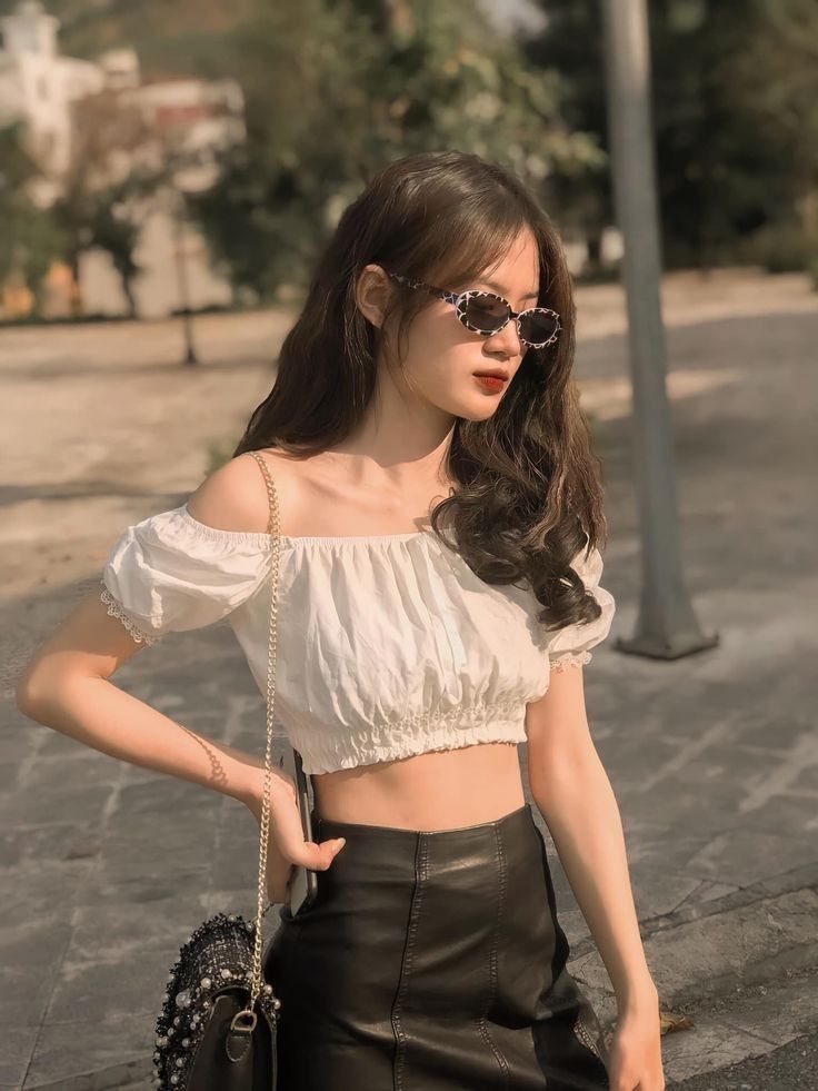 Cô gái trẻ xinh đẹp trong áo crop top trắng và chân váy đen