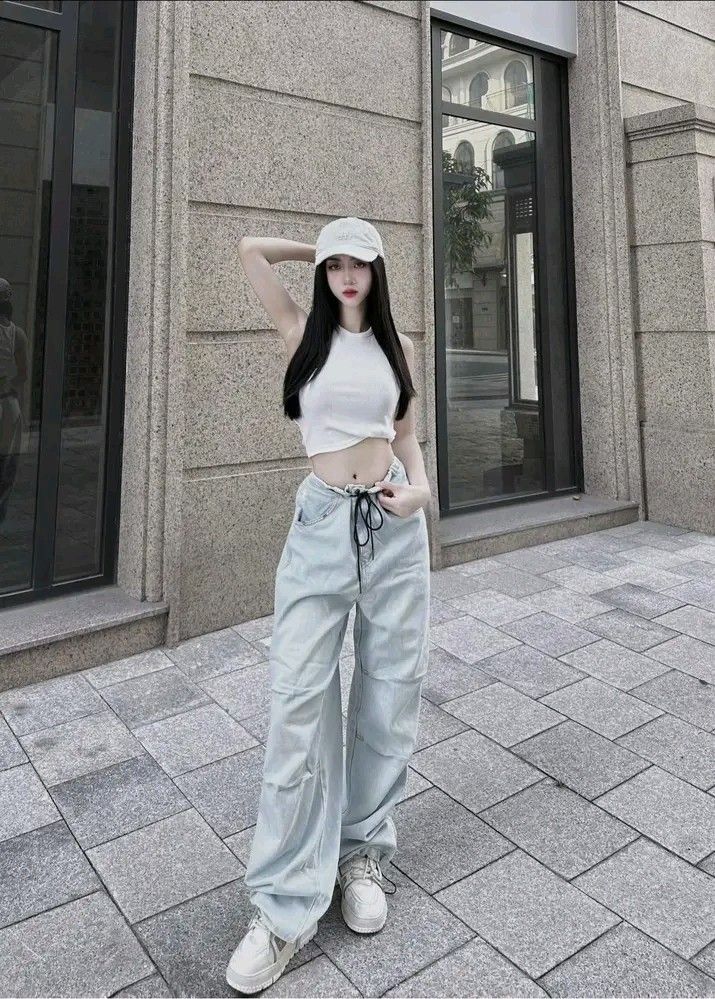 Cô gái trẻ xinh đẹp trong áo crop top trắng và quần jean sáng màu