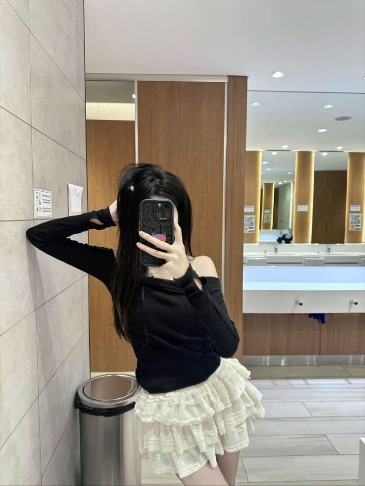 Cô gái trẻ xinh đẹp trong áo dài tay màu đen và chân váy xòe trắng