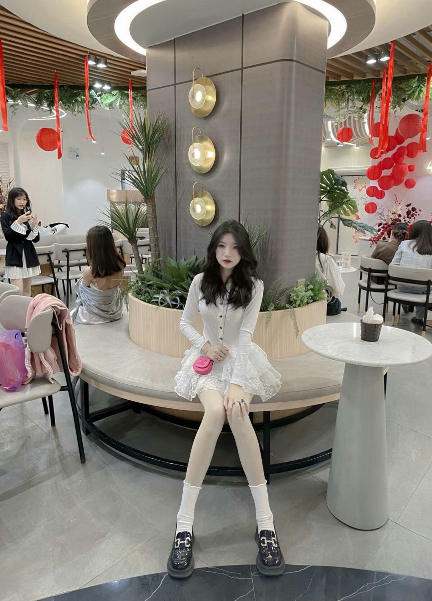Cô gái trẻ xinh đẹp trong áo sơ mi trắng và chân váy xòe