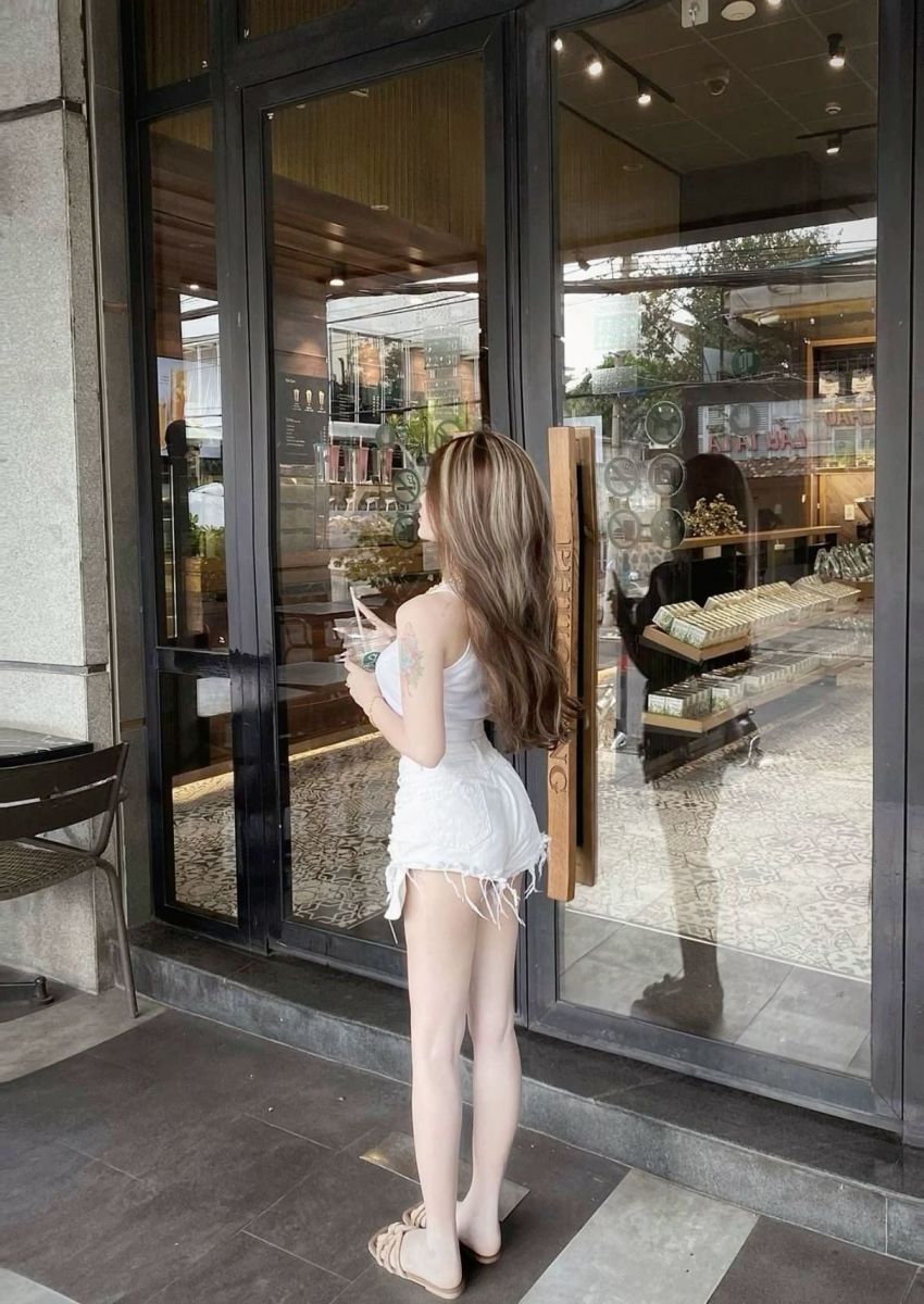 Cô gái trẻ xinh đẹp trong áo thun trắng và quần short