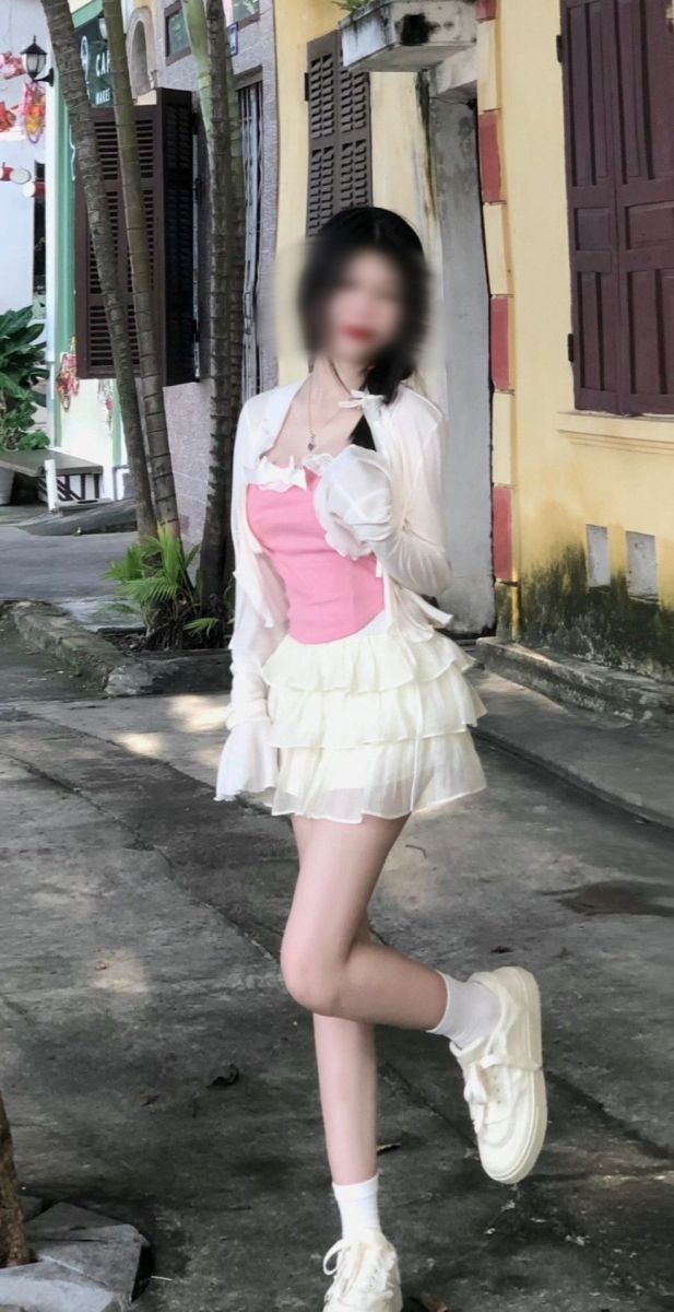 Cô gái trẻ xinh đẹp trong bộ váy trắng nổi bật giữa phố