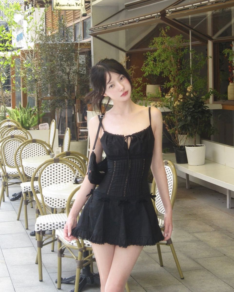 Cô gái trẻ xinh đẹp trong chiếc váy đen giữa quán cà phê