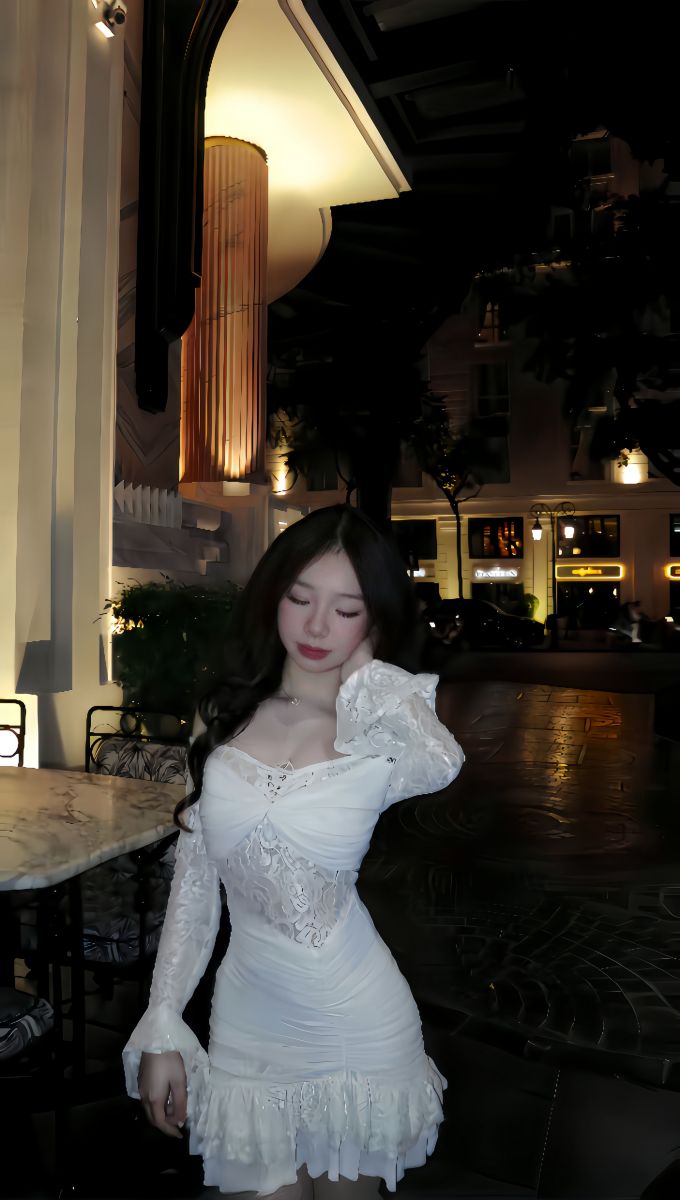 Cô gái trẻ xinh đẹp trong chiếc váy trắng tại quán cafe