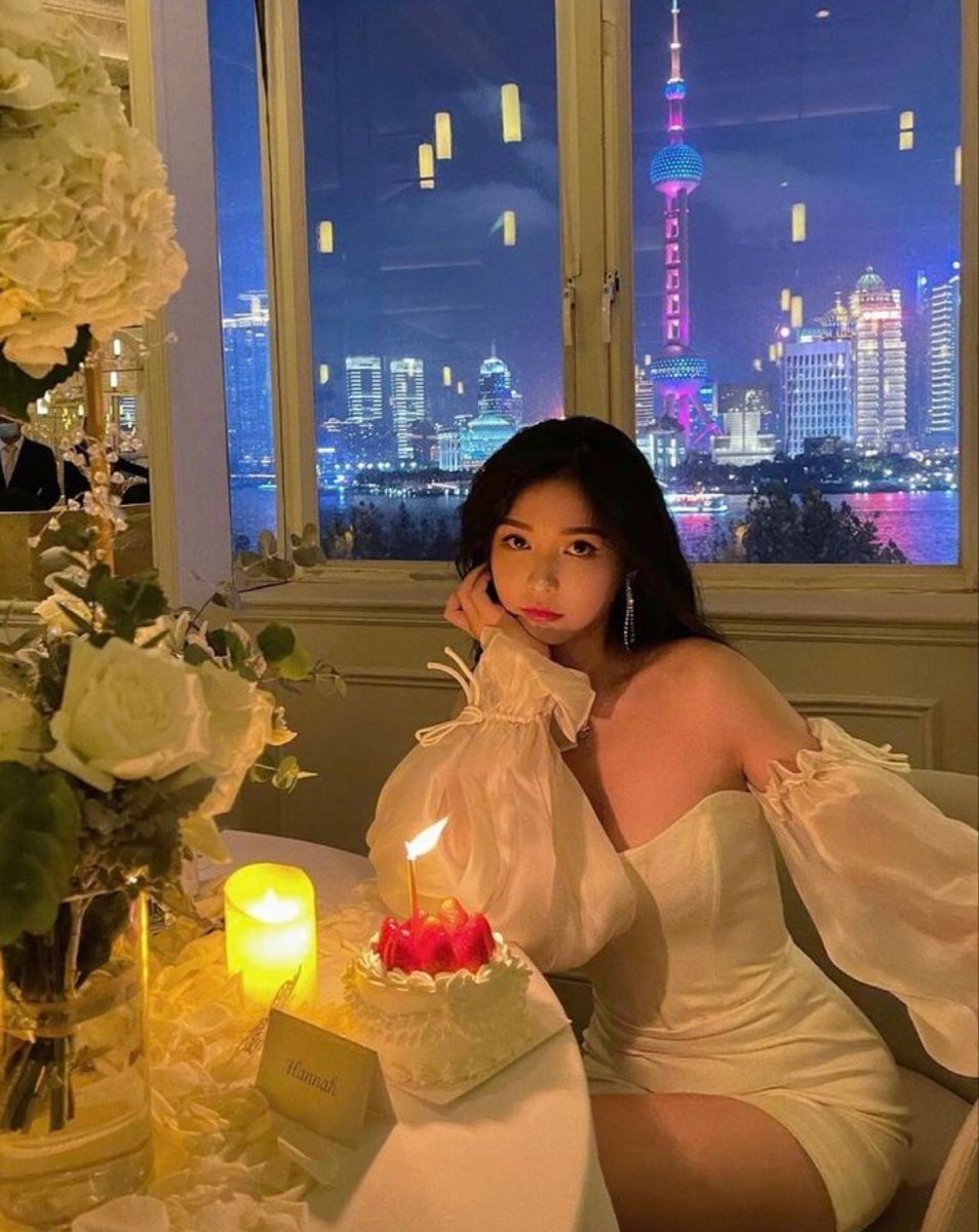 Cô gái trẻ xinh đẹp trong đầm trắng bên bàn ăn hoa tươi