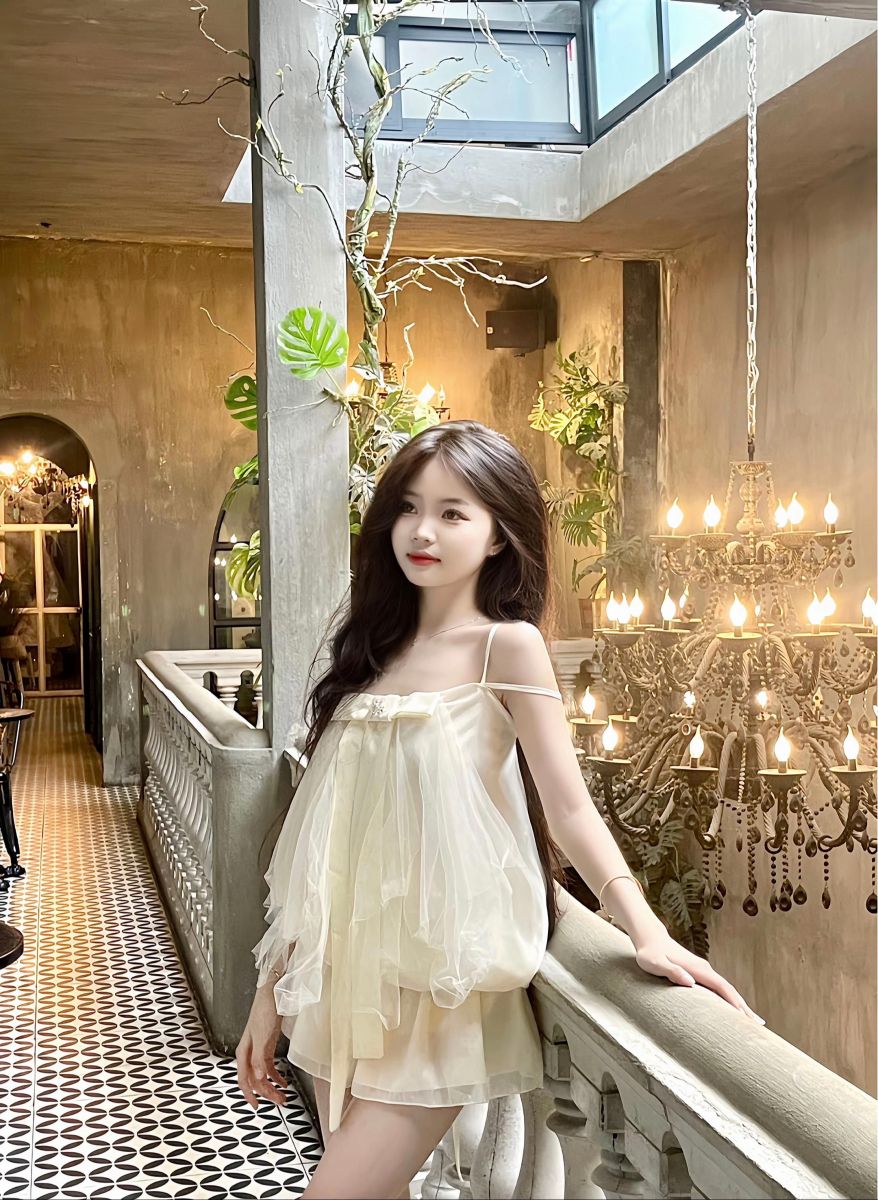 Cô gái trẻ xinh đẹp trong váy trắng nhẹ nhàng tại quán cà phê