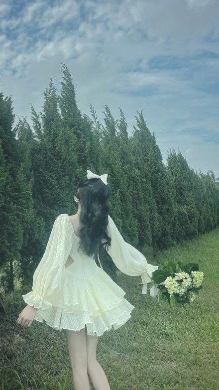 Cô gái trong chiếc đầm trắng quyến rũ bên cạnh hàng cây xanh