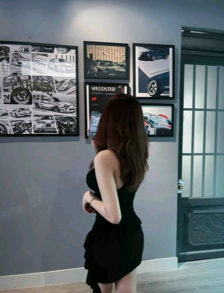 Cô gái xinh đẹp ngắm tranh xe hơi trong bộ váy đen