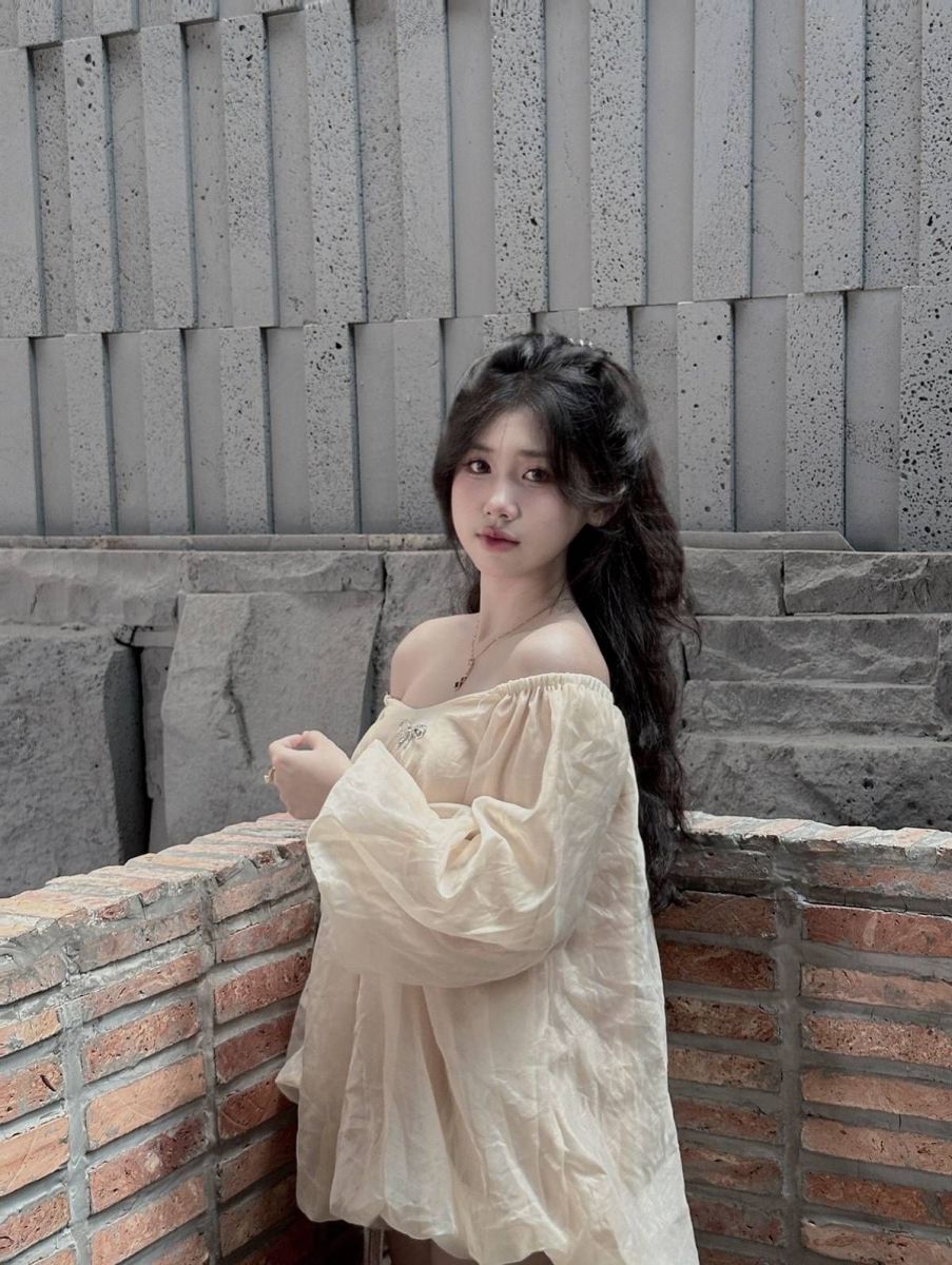 Cô gái xinh đẹp trong áo blouse màu kem tạo dáng nghệ thuật